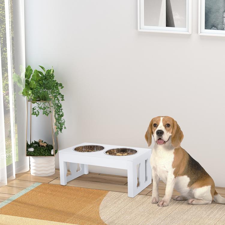 White elevated dog feeding station with two stainless steel bowls; dog eating