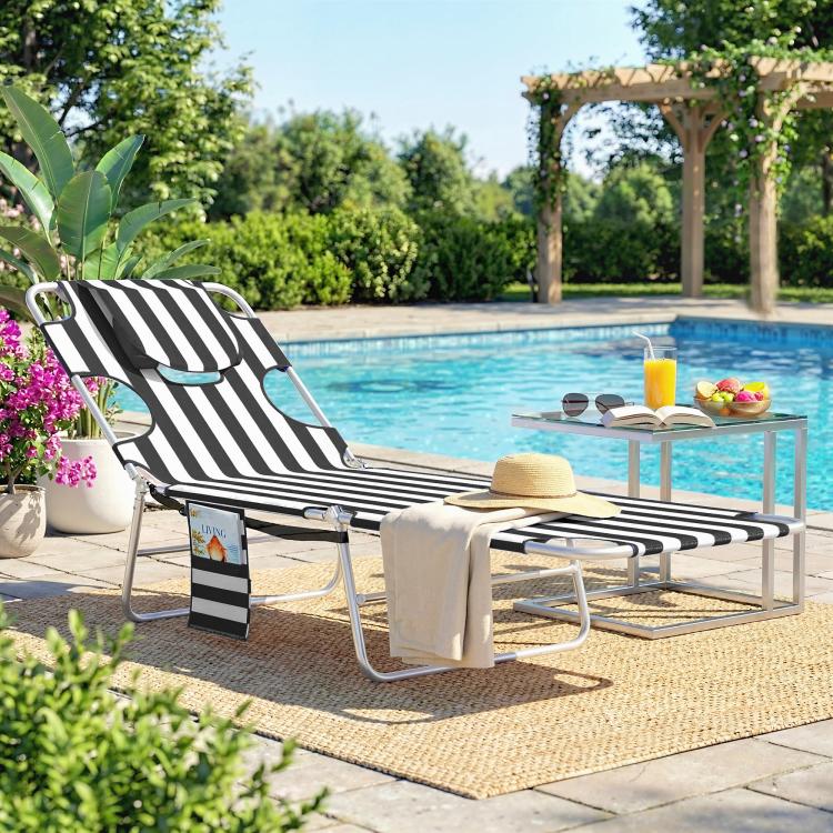 Outdoor tanning chaise lounge with black-and-white stripes, face hole, and cushioned head pillow