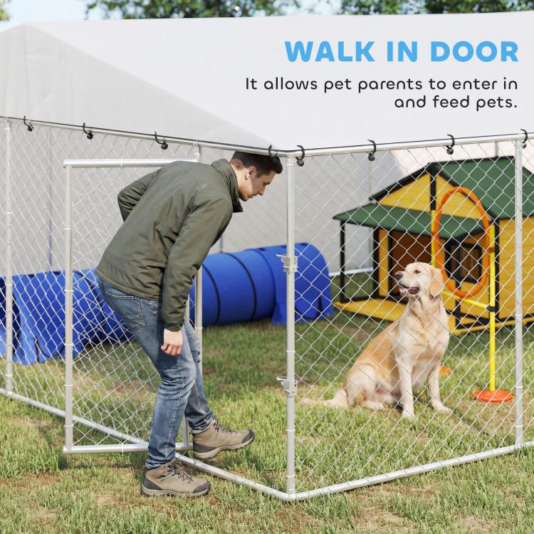 Outdoor dog kennel with silver frame and gray waterproof roof; person at front door with dog