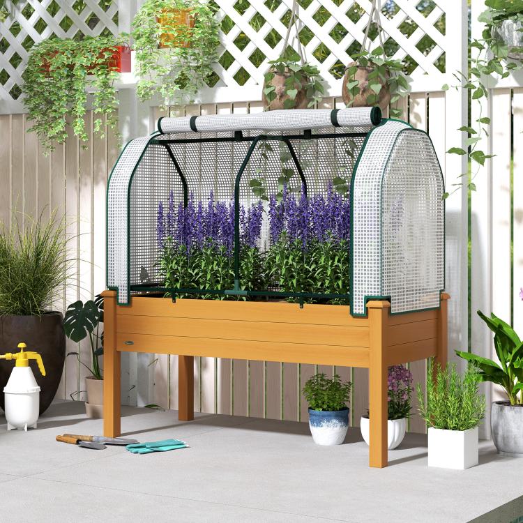 Raised garden bed planter with white mesh greenhouse cover and herbs growing inside