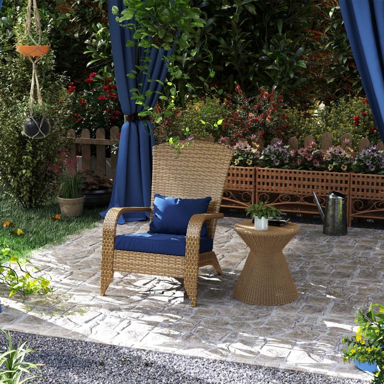 Rattan wicker outdoor Adirondack chair with dark blue cushions on stone patio