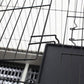 Black wire small animal cage with door latch and metal frame bars, close-up