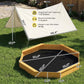 Yellow octagon wooden sandbox with dark bottom liner and curved bench seats.