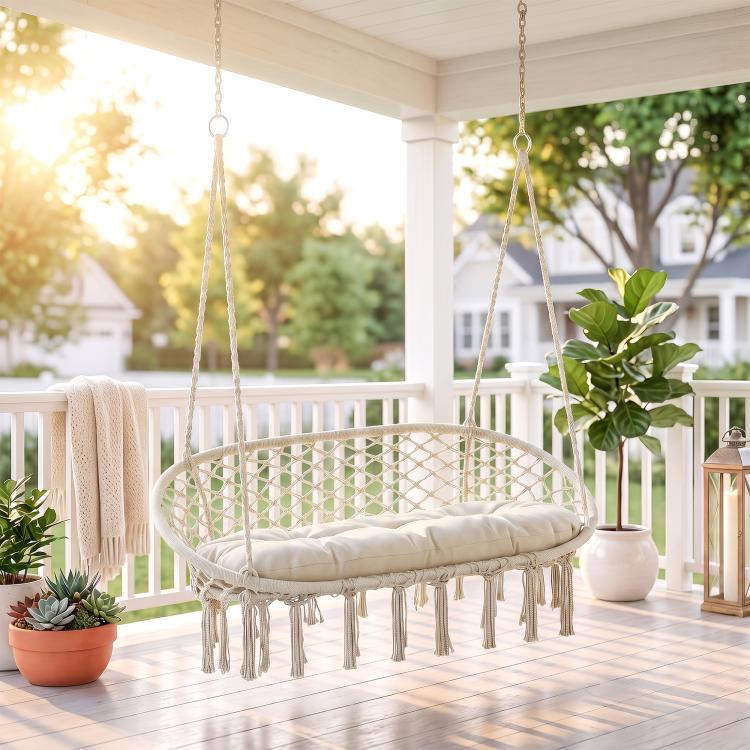 Hanging macrame hammock chair with round net seat, cream cushion, and white rope