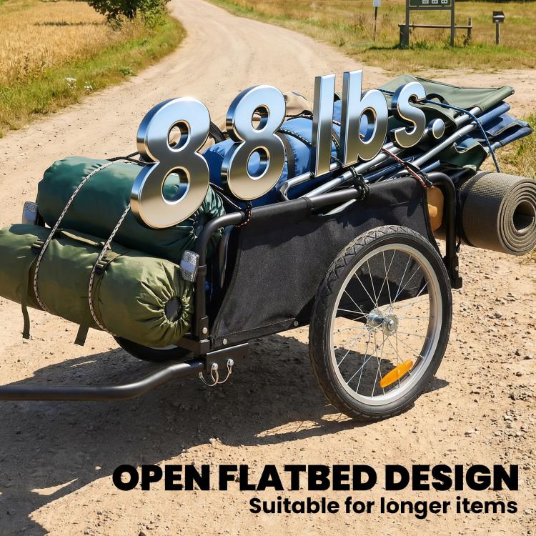 Bike cargo trailer with open flatbed and large pneumatic wheels, loaded with rolled gear and bags