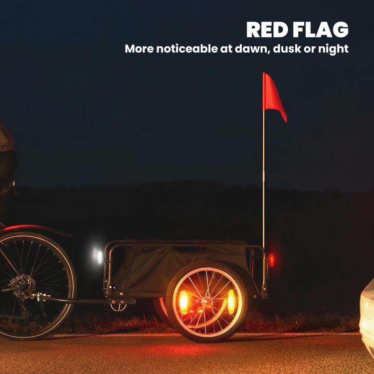 Bike cargo trailer at night with red safety flag and illuminated wheel, black open bed