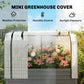 Clear greenhouse cover over raised garden bed with mesh panels and dark gray base