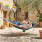 Two-person gray outdoor hammock with pillow, draped fabric and wooden spreader bars