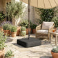 Black umbrella base with square cover on stone patio near outdoor seating