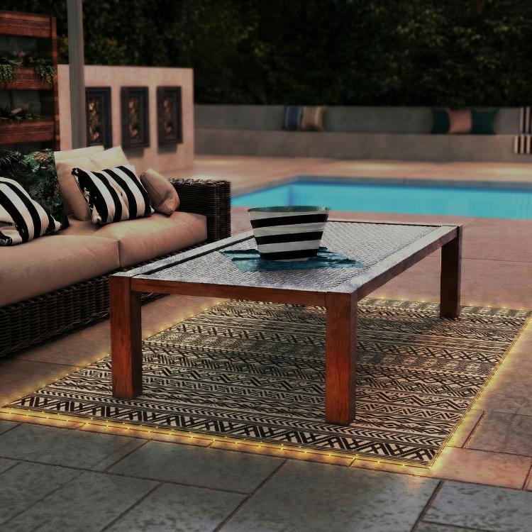 Outdoor patio rug with black-and-white geometric weave and visible border edge.