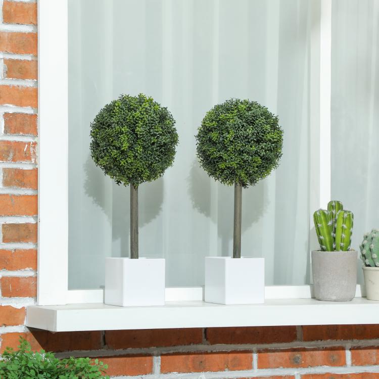 Pair of green boxwood-style topiary balls on wooden stems in white square planters