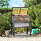 Gray raised planter box with mini greenhouse cover and pink flowers in garden