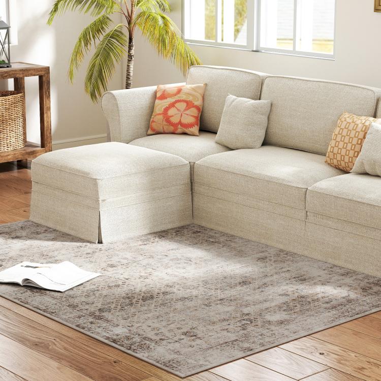Gray and tan distressed area rug under beige sectional sofa
