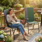 Dark green folding high-back chair with armrests, padded seat and back on patio