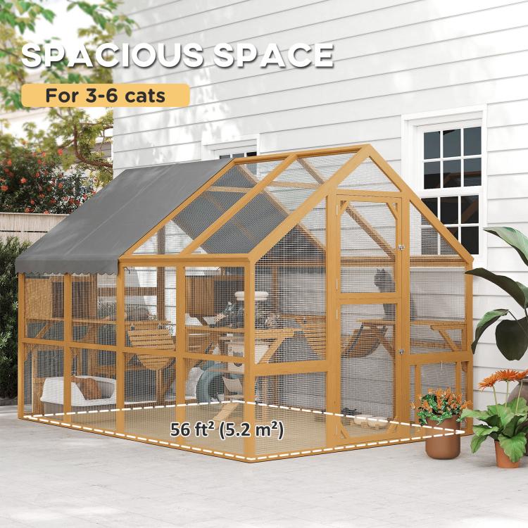 Large outdoor wooden cat house with gray roof cover, wire mesh panels, and cat activity areas