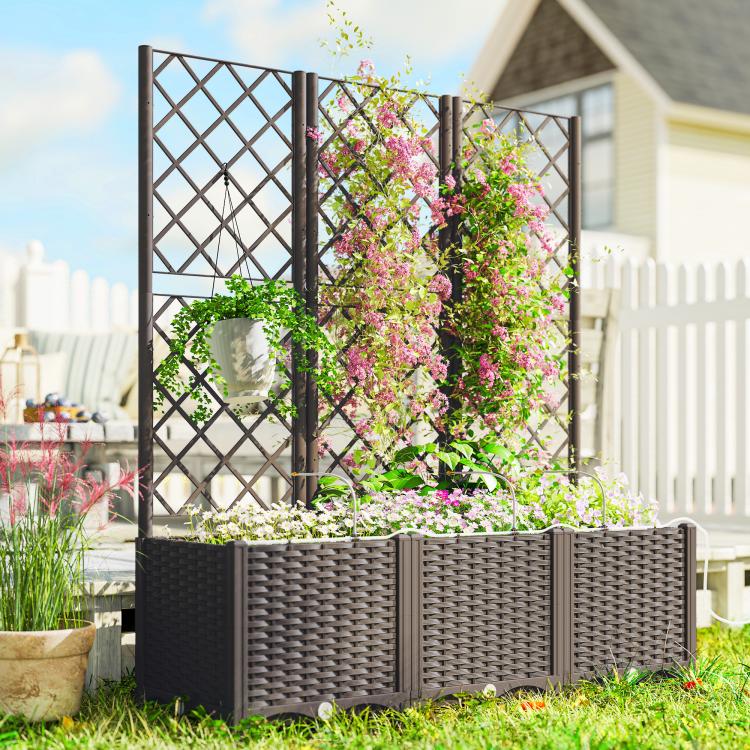 Raised garden planter bed with tall trellis and abundant pink flowers in outdoor yard