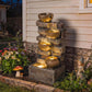 Outdoor tiered jug fountain with flowing water and warm illuminated LEDs