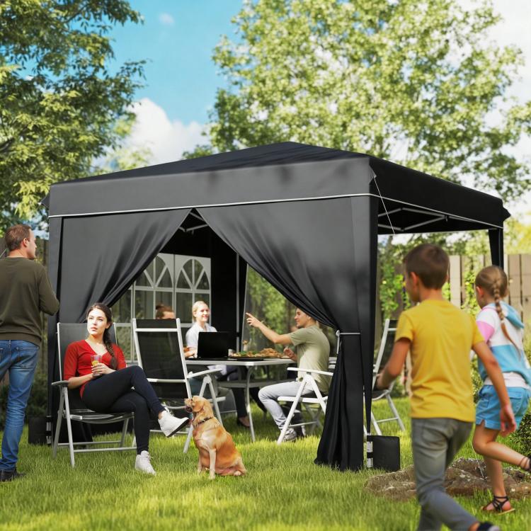 Black outdoor canopy tent with attached side panels and window panels over grass