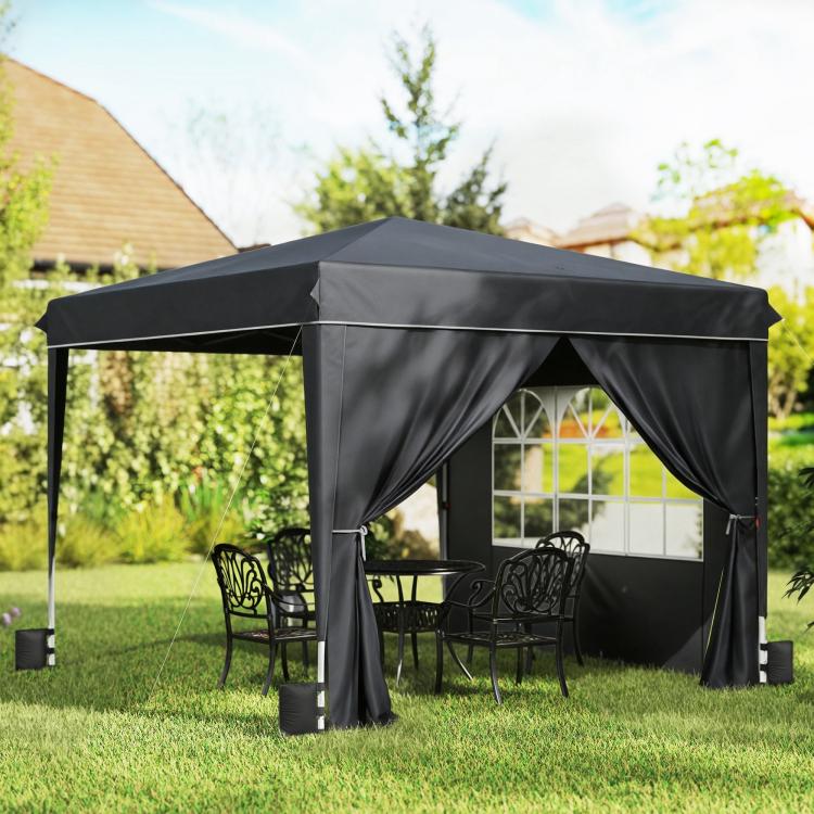 Black pop-up canopy tent with sidewalls and dark curtains, set over a backyard lawn