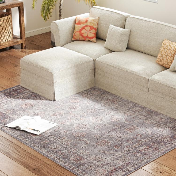 Grey and brown floral area rug with border pattern, placed under a living room sofa