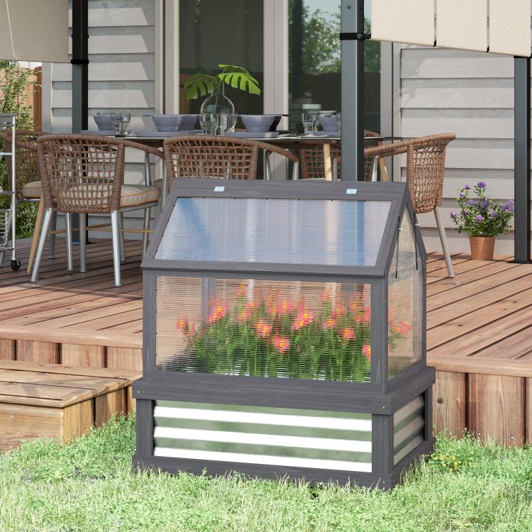 Gray wooden greenhouse cold frame planter on grass with transparent cover