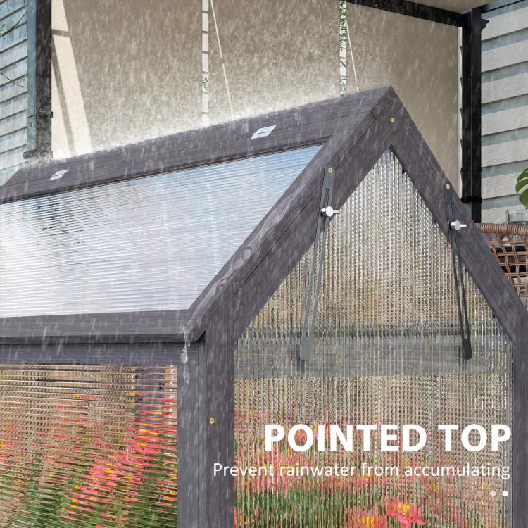 Gray wooden greenhouse cold frame with pointed roof to help shed rainwater