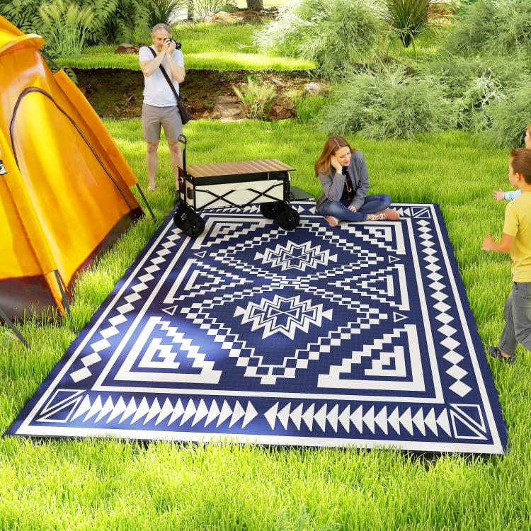 Blue and white outdoor rug with bold geometric pattern on grass