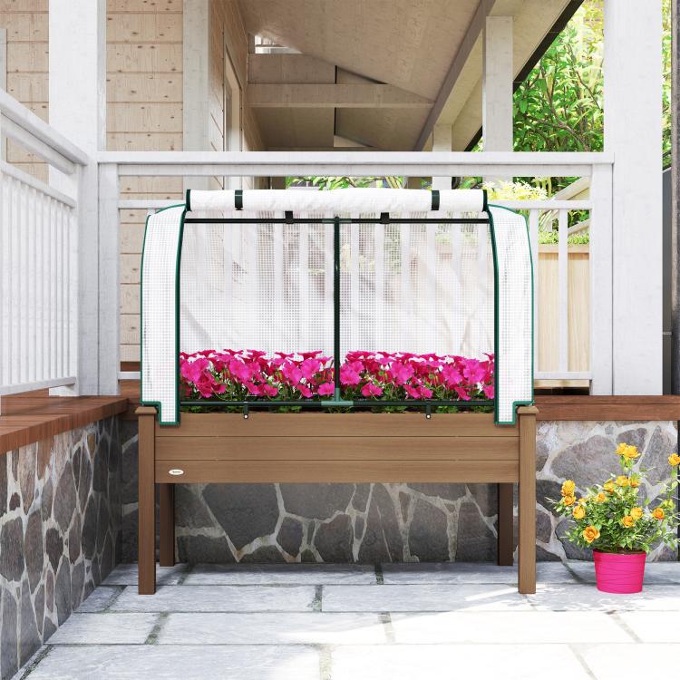 Brown raised garden bed with green greenhouse cover and mesh panels, pink flowers inside