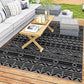 Reversible outdoor rug with black and gray geometric pattern, neatly laid on deck boards