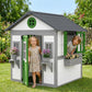 Outdoor white wooden playhouse with green door and two windows, with planter boxes
