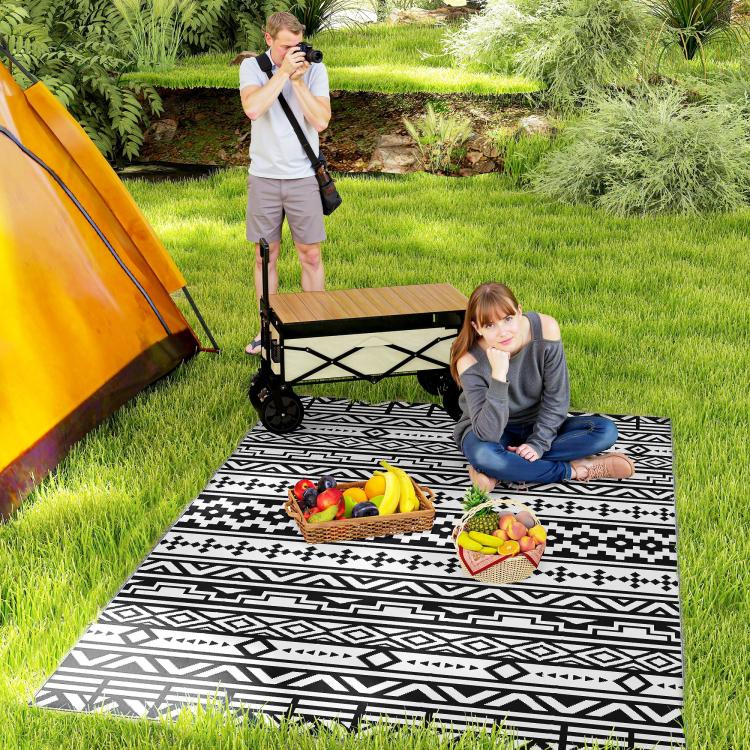 Black-and-white geometric outdoor rug laid on grass for camping