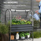 Dark gray raised garden bed with clear cover and person watering plants from side