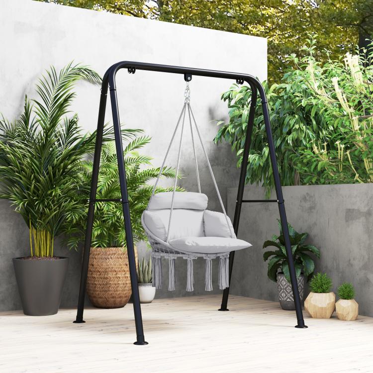 Gray macrame hammock chair with padded cushion and fringe tassels on black steel stand