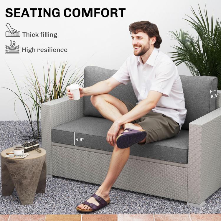 Gray outdoor loveseat cushions on a wicker bench, thick seat and two backs