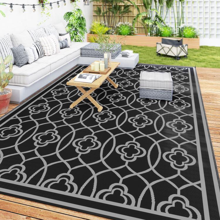 Outdoor rug with black background, gray quatrefoil pattern, and dark border