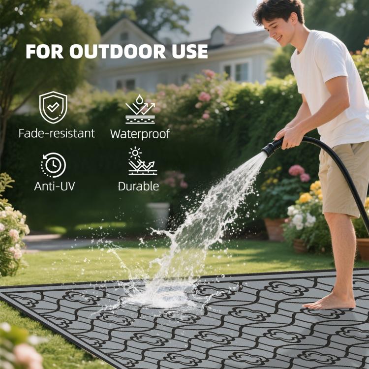 Outdoor waterproof rug with black-and-gray quatrefoil pattern on grass
