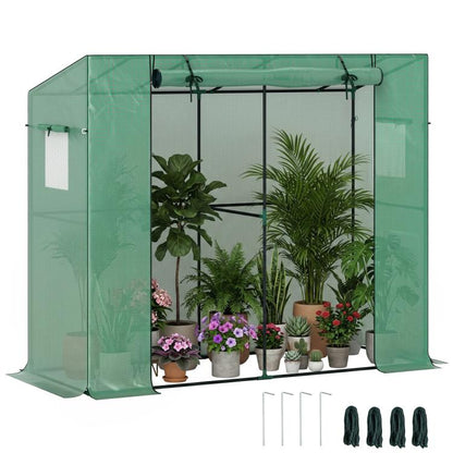 Green small walk-in greenhouse with roll-up door and clear front panels, outdoors