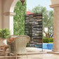 Black metal privacy screen with rectangular cutout stripes, freestanding on legs