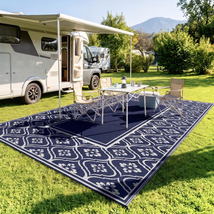 Outdoor rug with navy-and-white floral gourd border, laid on green lawn