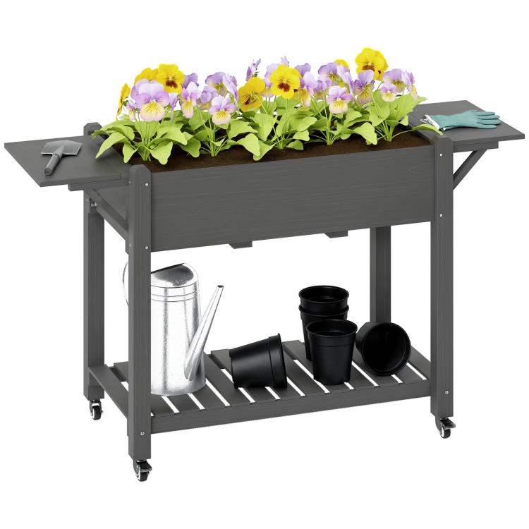 Gray wooden raised planter box with side tables, lockable wheels, and bottom shelf for pots