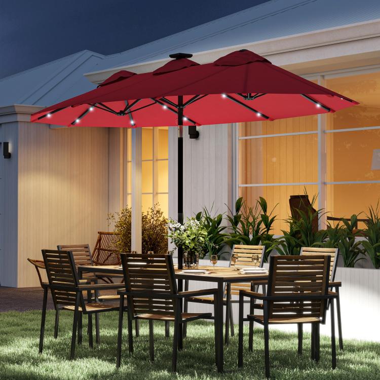 Wine red patio umbrella open over outdoor dining area, with LED string lights along ribs