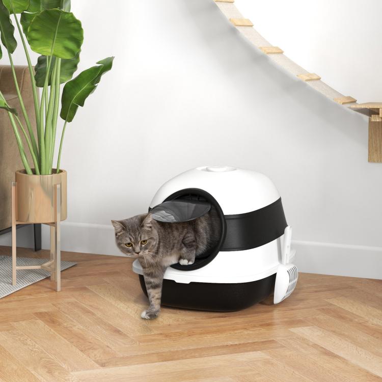 White and black dome cat litter box with lid, cat standing at open entry