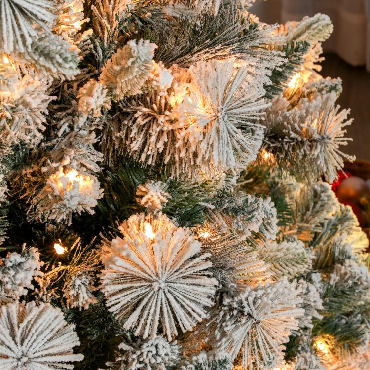 Flocked prelit artificial Christmas tree, close-up of snowy branches with clear lights