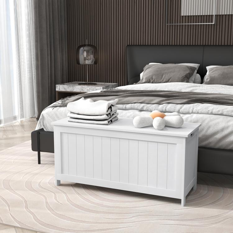 White wooden storage bench trunk holding folded blankets and pillows on top
