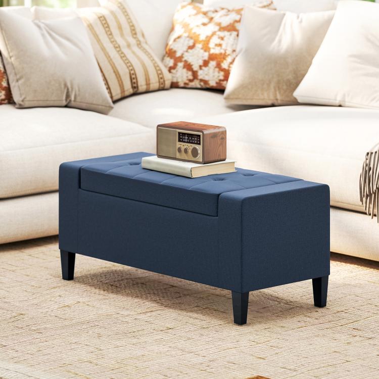 Dark blue upholstered lift-top storage ottoman bench with button tufting and short legs