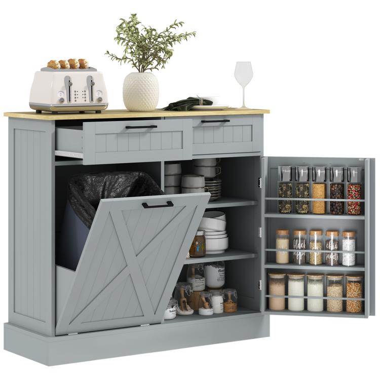 Gray kitchen cabinet with tilt-out trash door and open shelves, two drawer fronts visible.