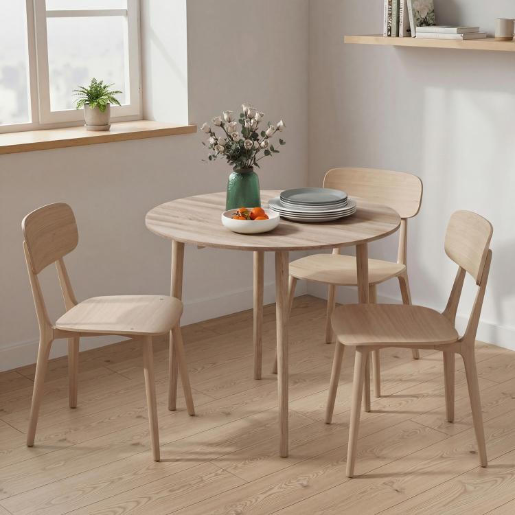 Round drop-leaf dining table with light oak top and four wooden legs in a corner dining area