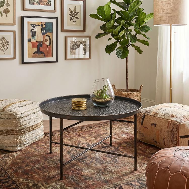 Round coffee table with hammered metal tray top and dark cross-braced metal base
