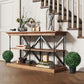 Artificial ball topiary trees with black pots on a wooden console table.