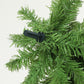 Green artificial Christmas tree branch tips with black bend connector close-up